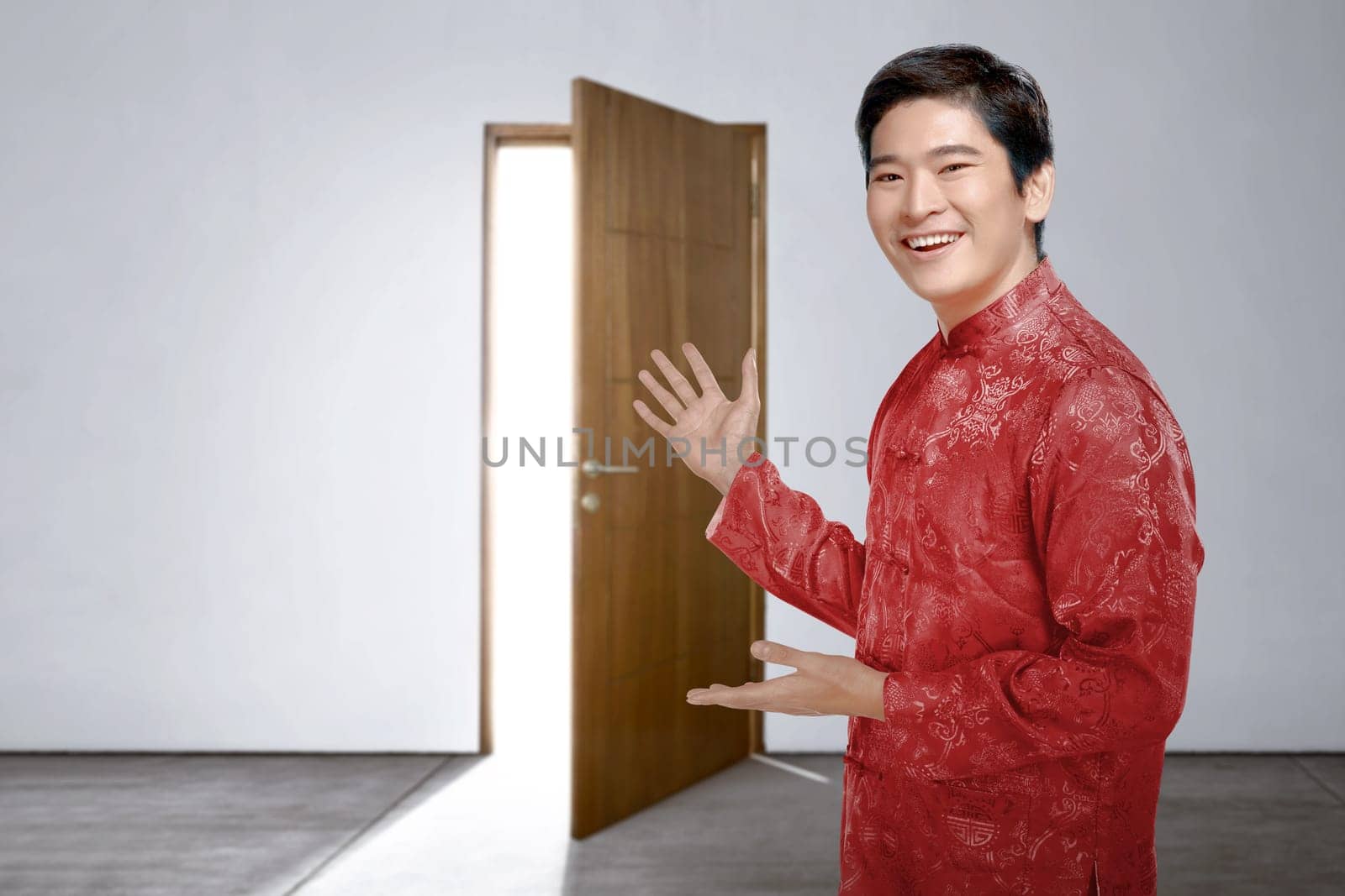 An Asian Chinese man in cheongsam dress invites into the house to celebrate Chinese New Year. Happy Chinese New Year