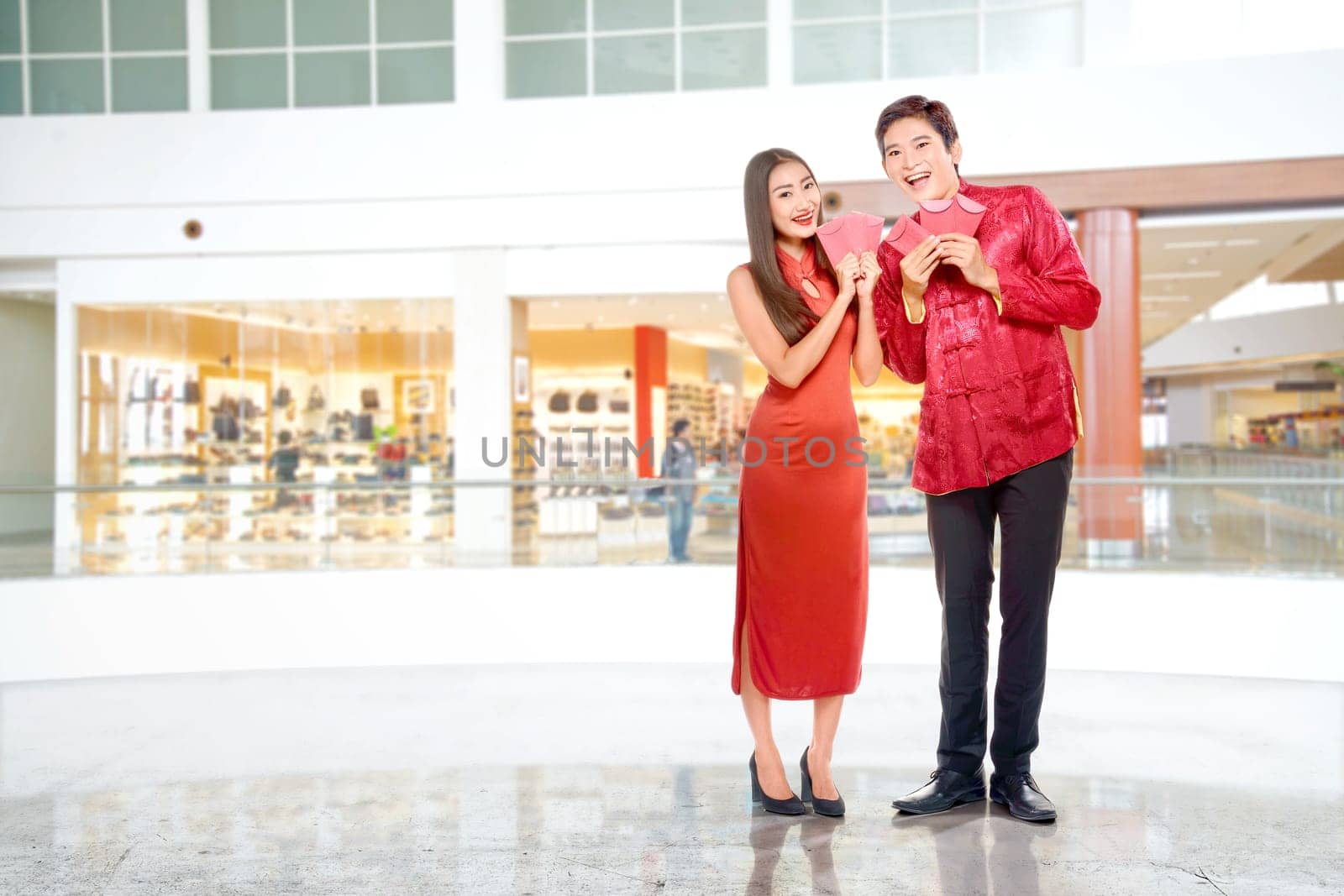 Asian Chinese couple in cheongsam dress holding red envelopes. Happy Chinese New Year