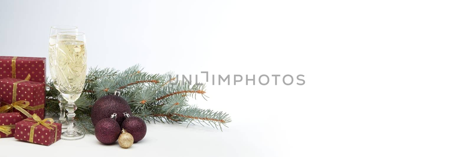 Still life with two champagne flutes, gift boxes and Christmas decoration with fir tree branch on white background with copy space. Christmas and New Year shopping. Greeting card