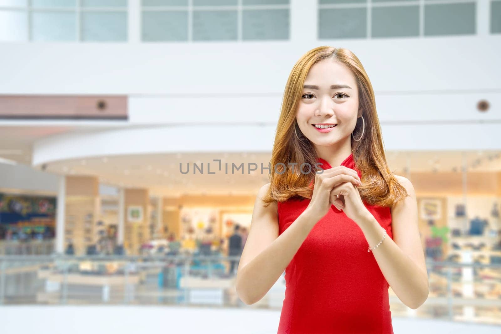 Asian Chinese woman in a cheongsam dress with congratulations gesture. Happy Chinese New Year