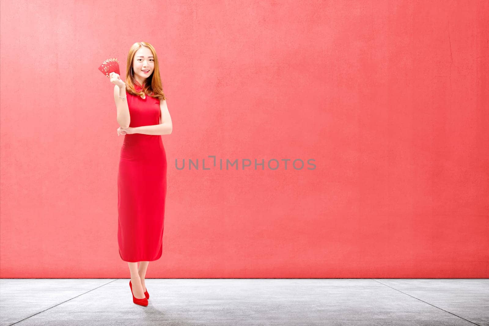 Asian Chinese woman in a cheongsam dress holding red envelopes. Happy Chinese New Year