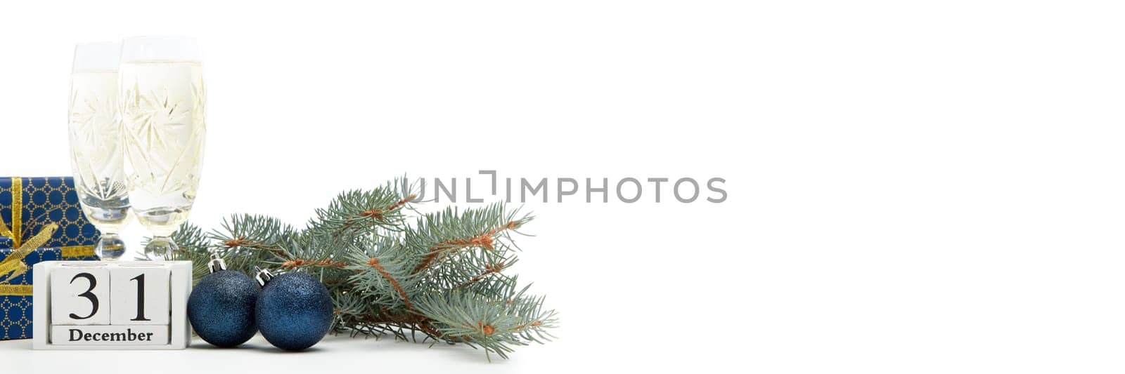 Still life with two champagne flutes, gift boxes and decoration with fir tree branch isolated on white background with copy space. New Year shopping. Greeting card