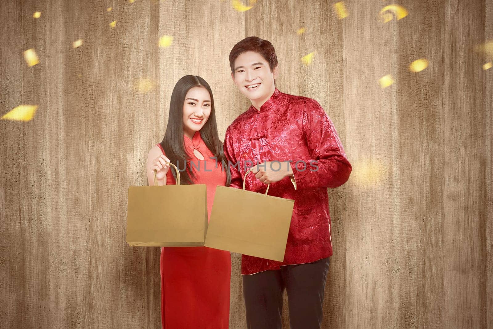 Asian Chinese couple in cheongsam dress holding shopping bags. Happy Chinese New Year
