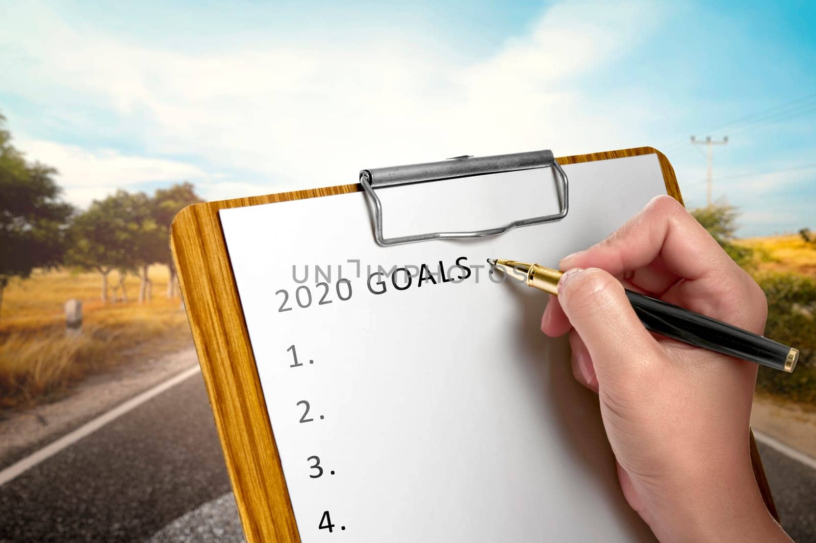 Human hand writes a list for 2020 goals in the paper on clipboard. Goals of 2020. Happy New Year 2020
