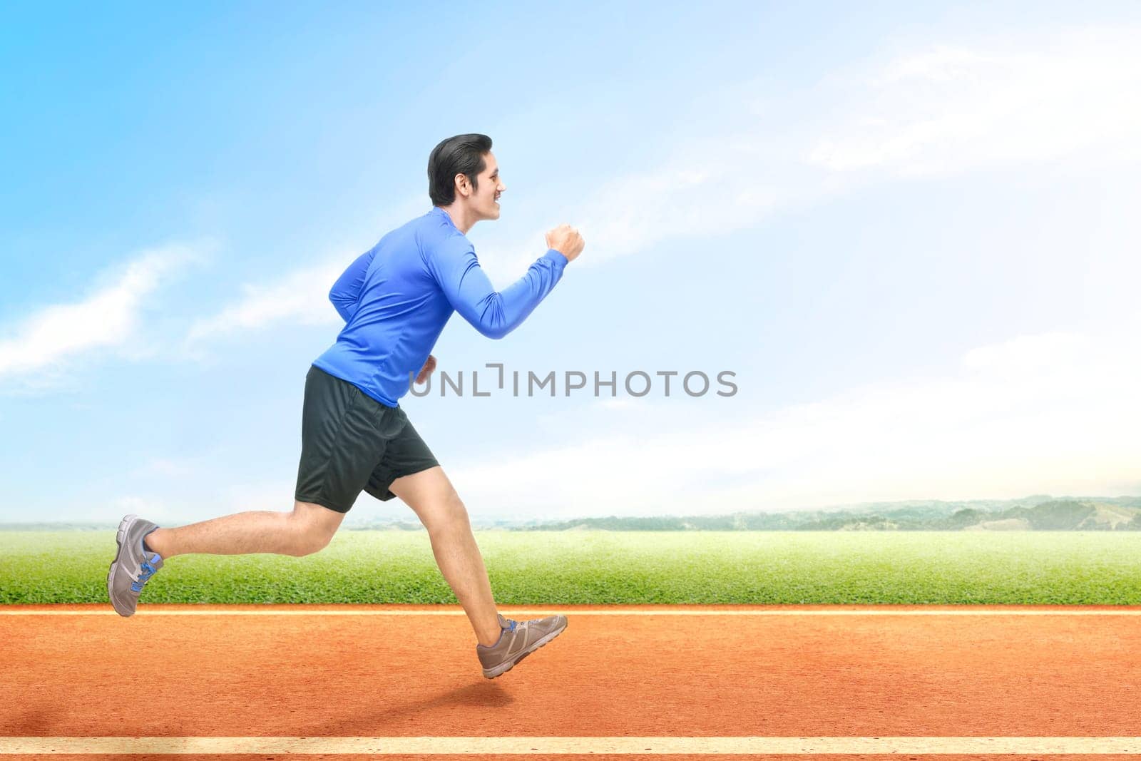 Asian runner man running on the running track with a blue sky background