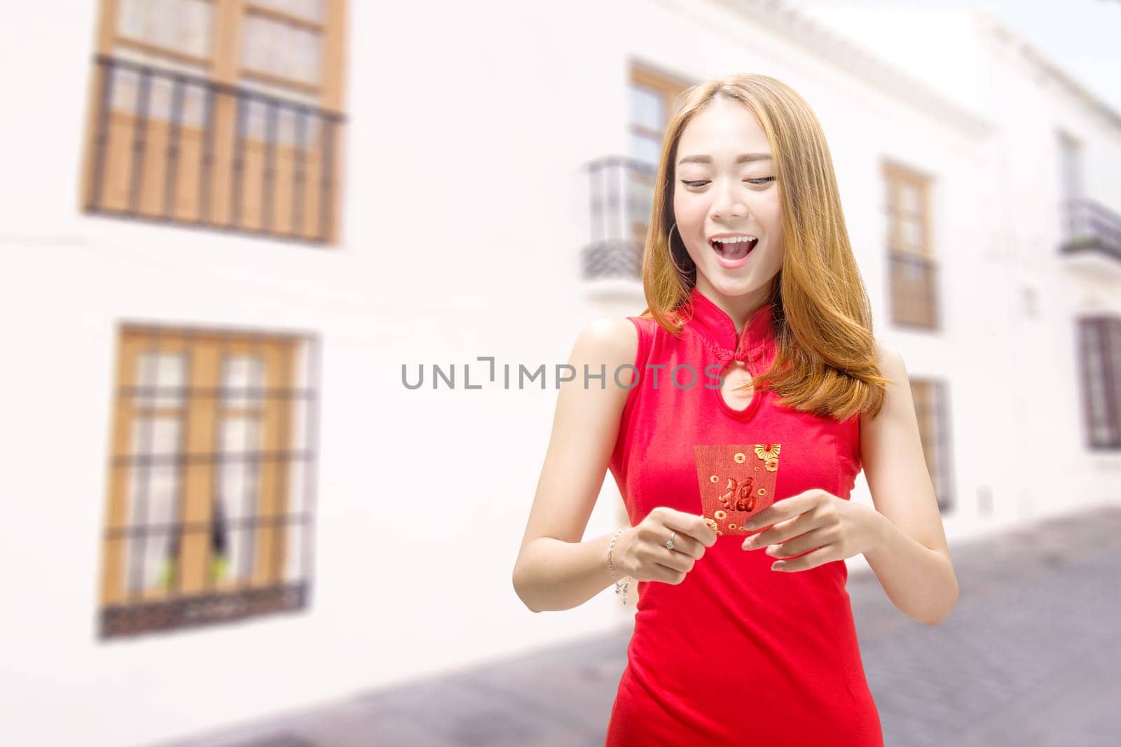 Asian Chinese woman in a cheongsam dress holding red envelopes. Happy Chinese New Year