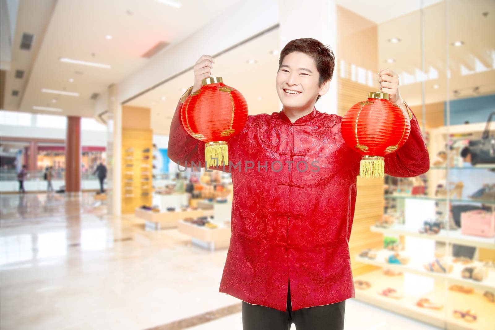 An Asian Chinese man in a cheongsam dress holding Chinese lantern. Happy Chinese New Year