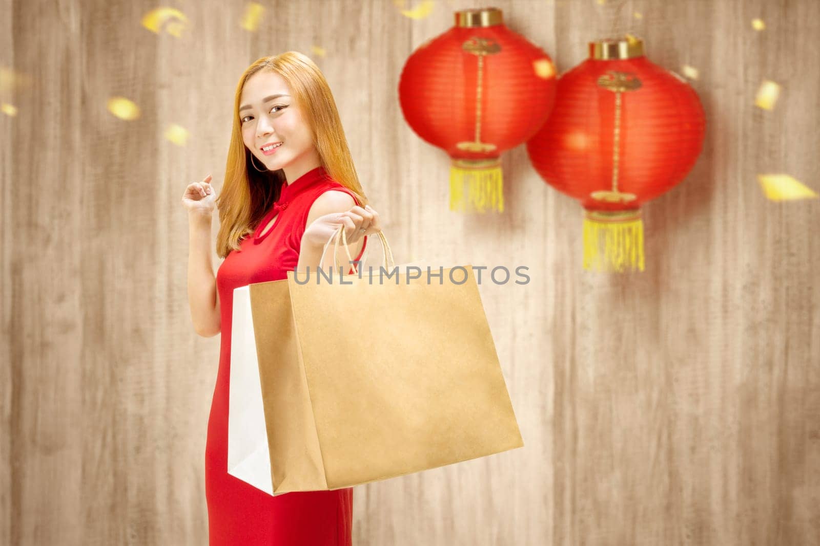 Asian Chinese woman in cheongsam dress holding shopping bags. Happy Chinese New Year