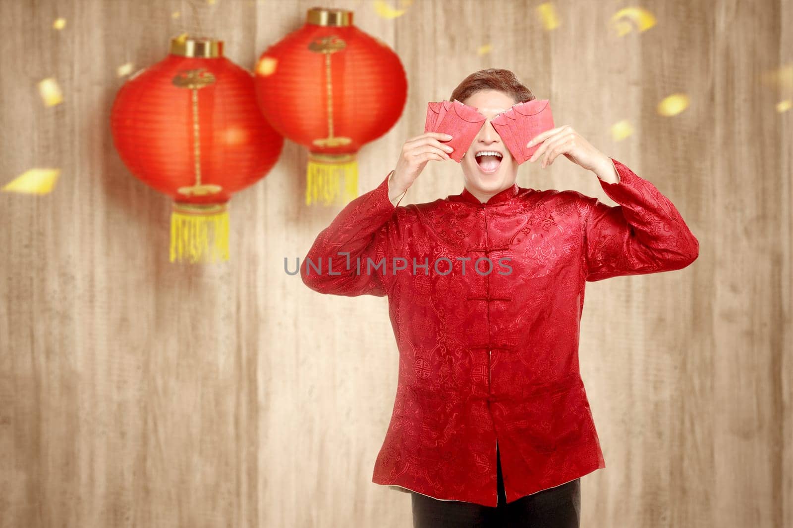 An Asian Chinese man in a cheongsam dress holding red envelopes. Happy Chinese New Year