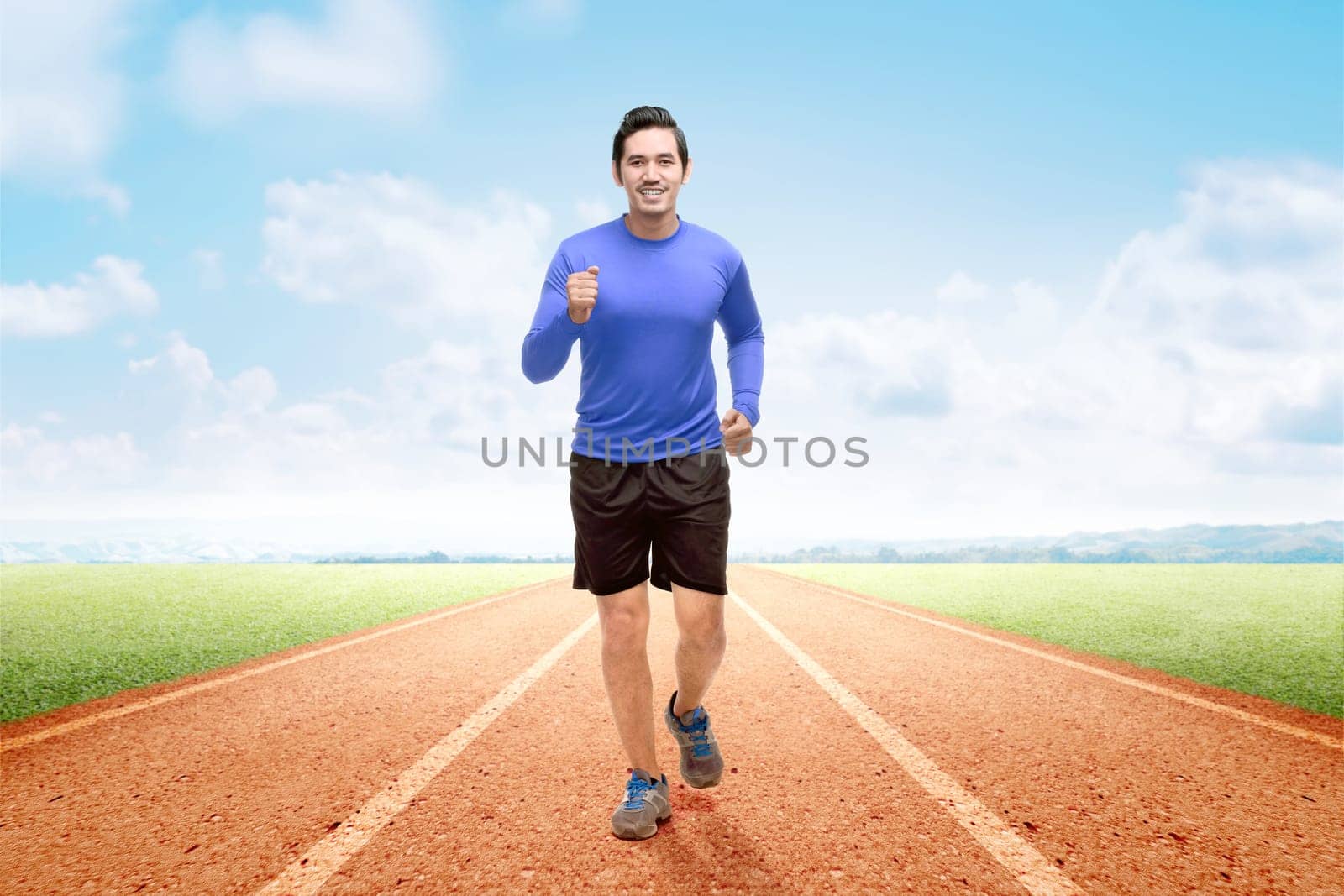 Asian runner man running on the running track with a blue sky background