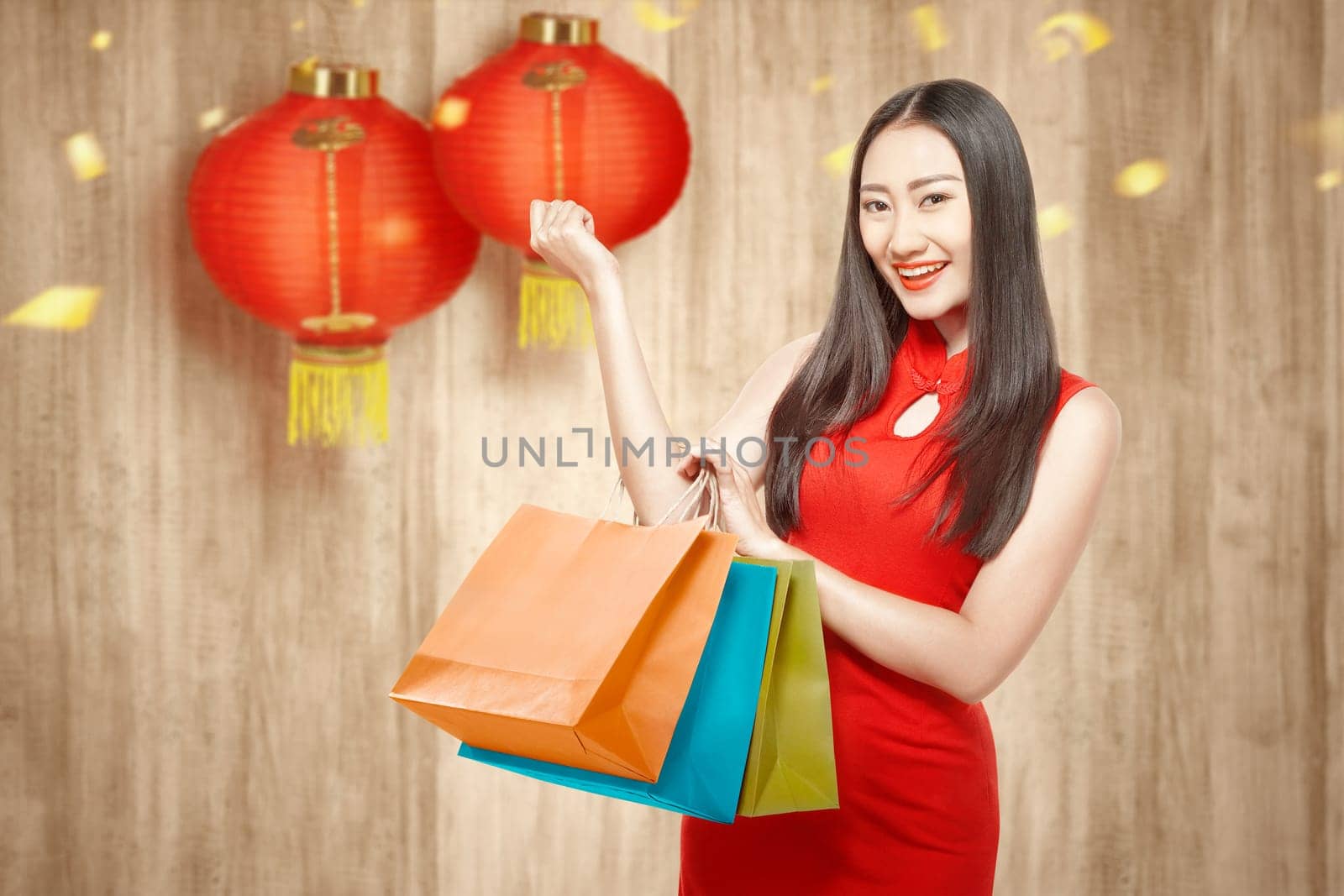 Asian Chinese woman in cheongsam dress holding shopping bags. Happy Chinese New Year