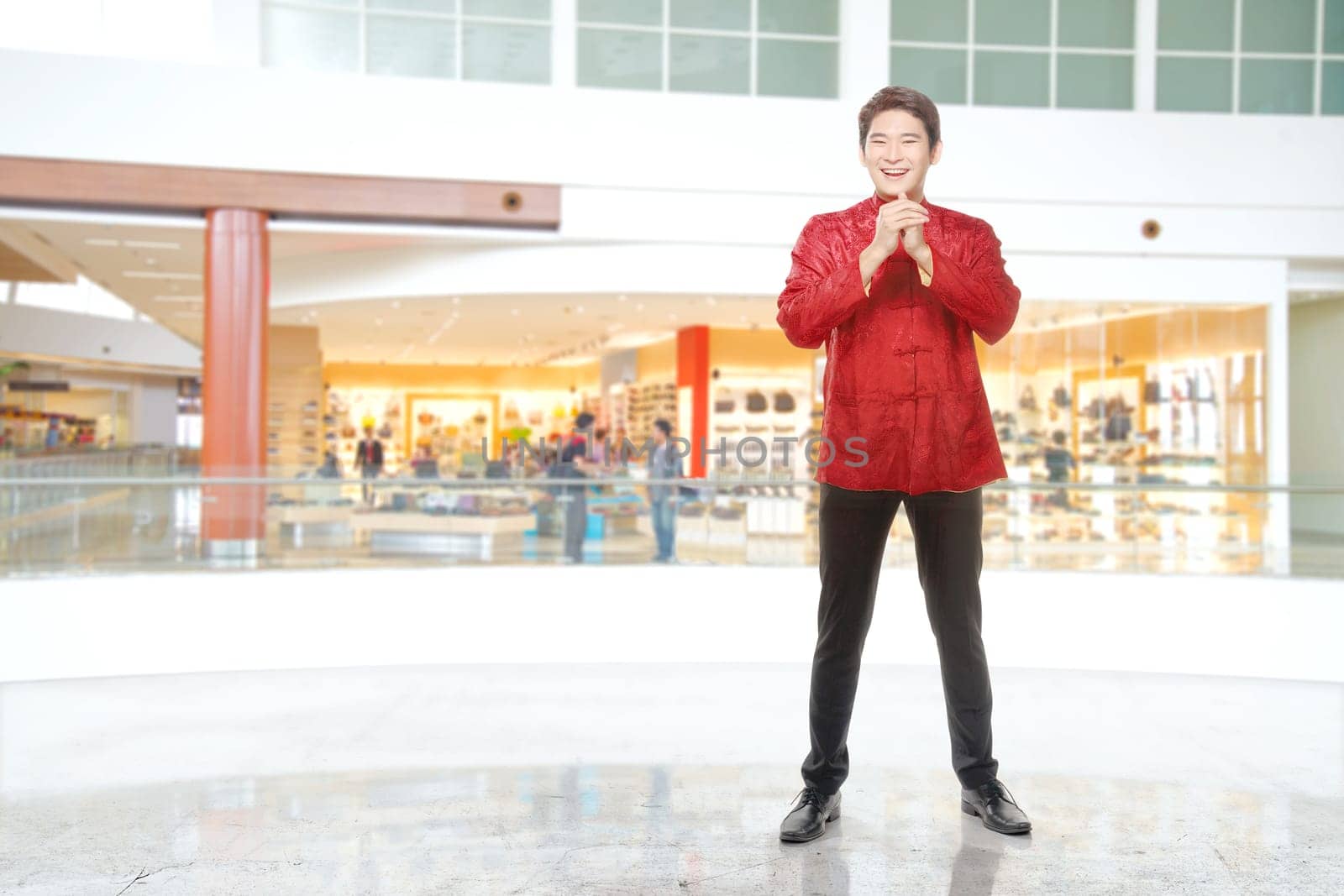An Asian Chinese man in a cheongsam dress with congratulations gesture. Happy Chinese New Year