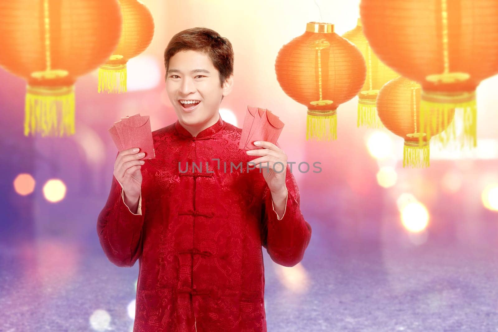 An Asian Chinese man in a cheongsam dress holding red envelopes. Happy Chinese New Year