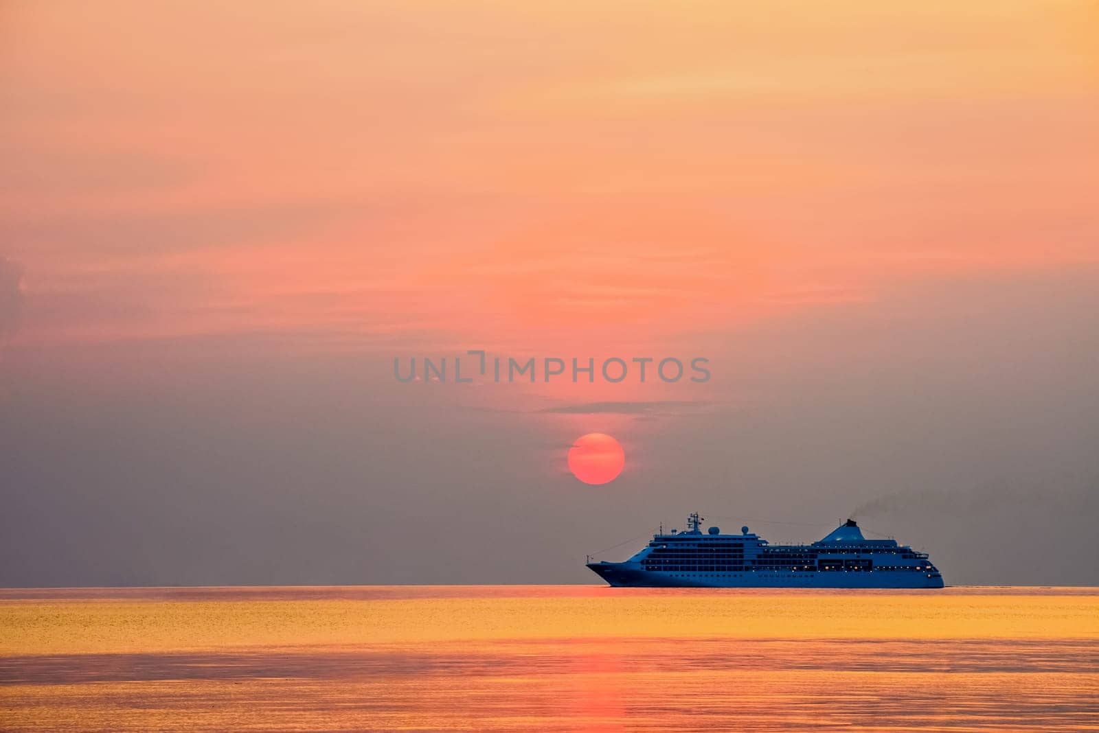 Travel by Cruise ship in the ocean, large luxury passenger boat is sailing on the bright sea, red sun in the colorful sky is yellow, orange, beautiful nature landscape at sunset or sunrise background