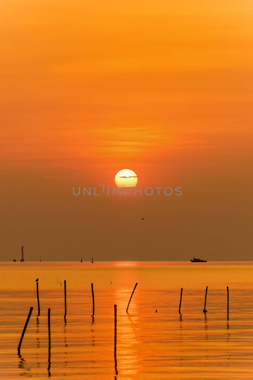 Beautiful nature landscape bright yellow sun reflecting orange light on the water surface of the sea and golden sunlight in sky, Colorful sunset at the tropical coast in Bangpu, Samut Prakan, Thailand