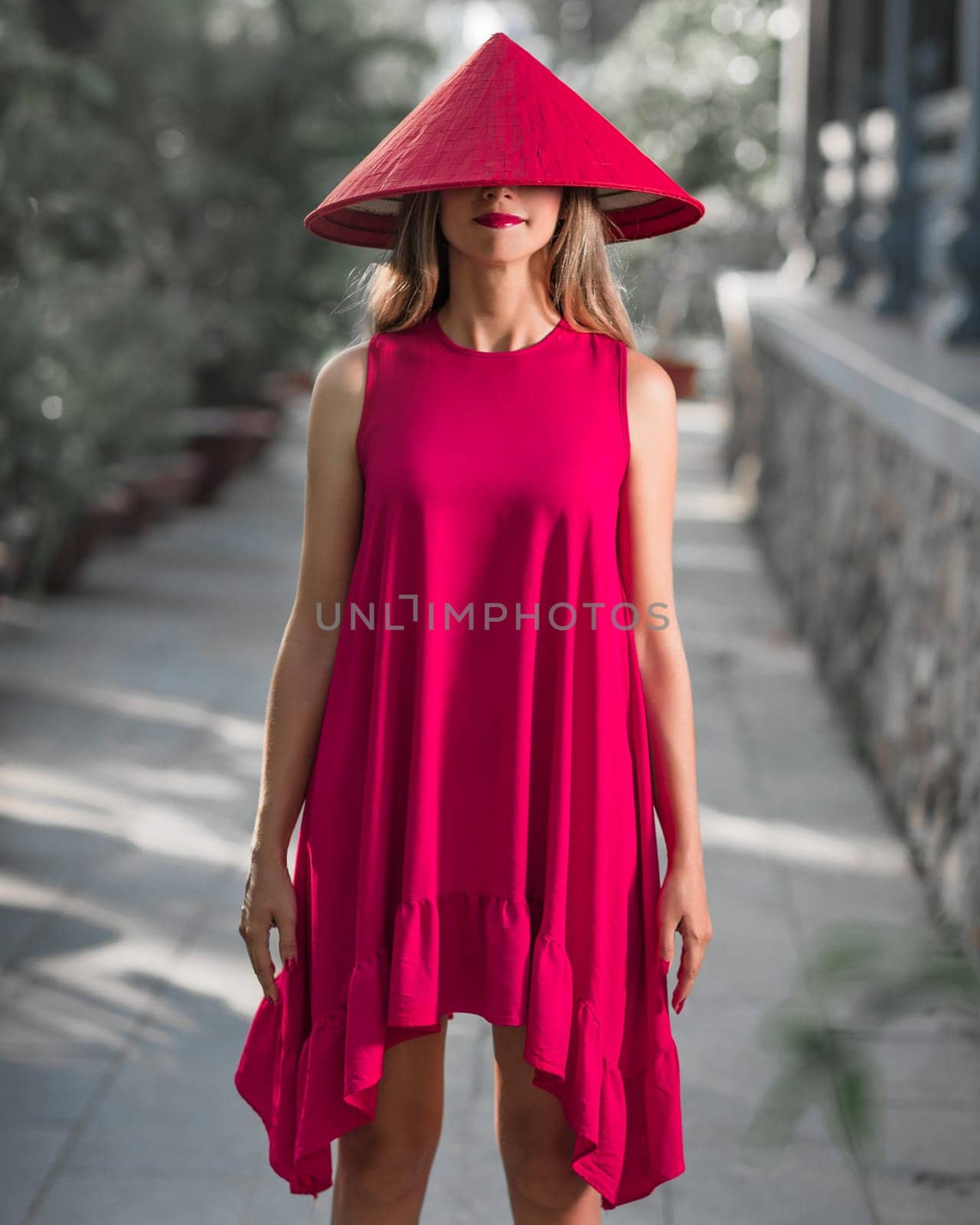 Fashion portrait of a beautiful woman in red conical hat outdoor