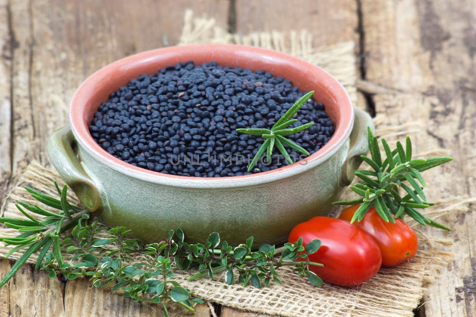 beluga lentils, tomatoes and herbs on wooden background