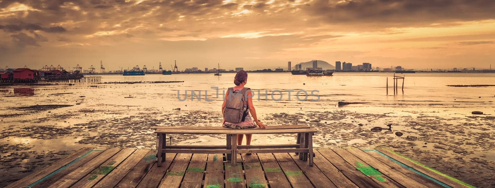 Tourist with backpack at Yeoh jetty at sunrise, Georgetown, Penang, Malaysia. Panorama