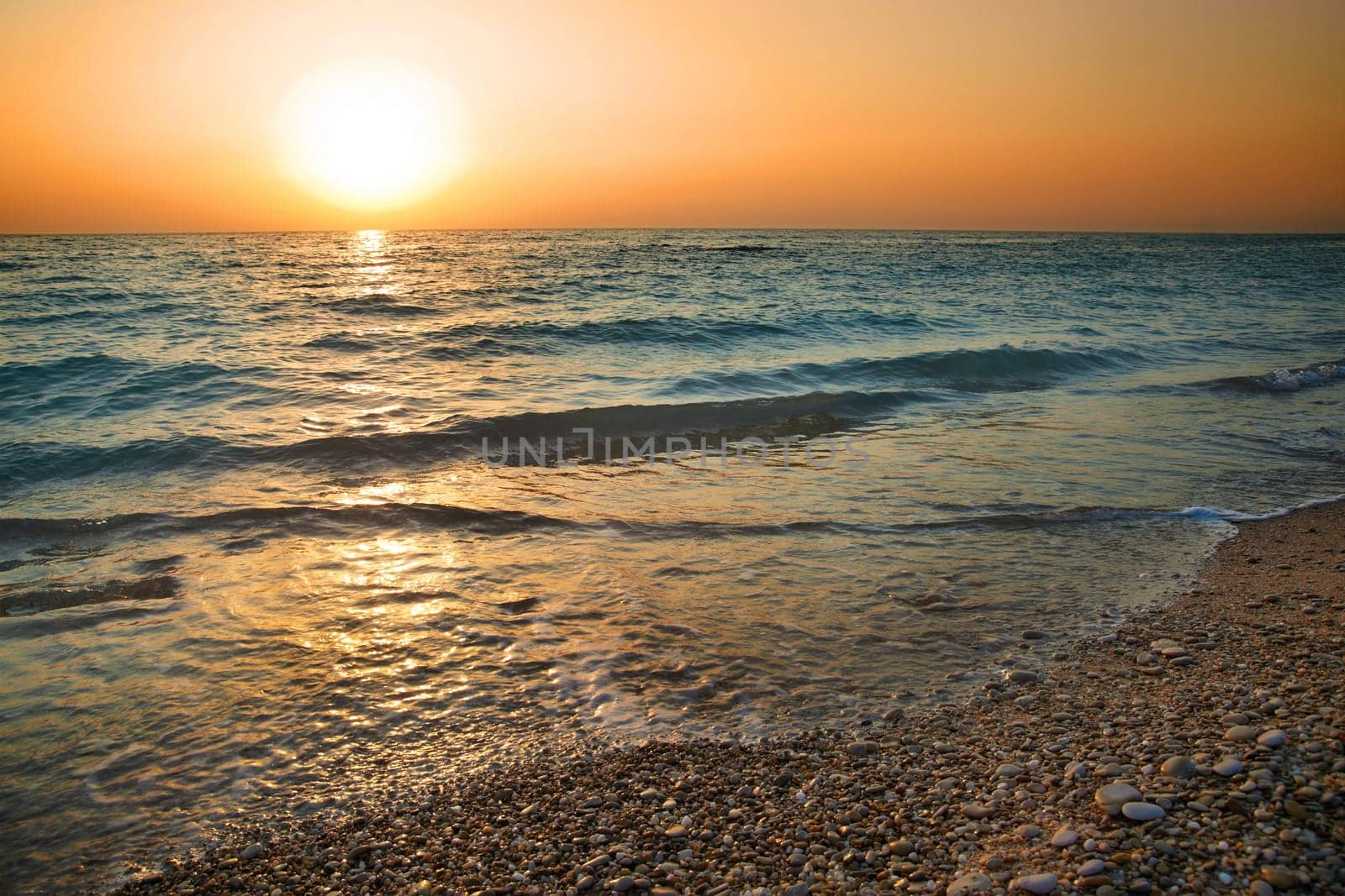 Sunset above the sea. Big sun and waves at beach