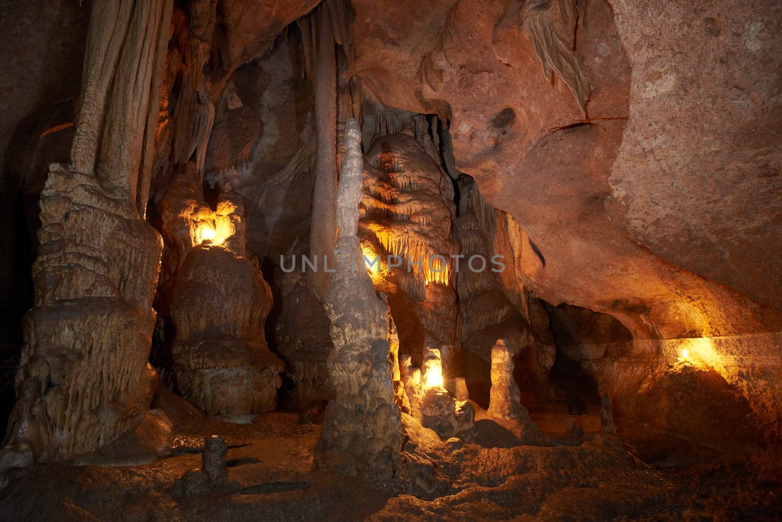 Unique cave formation - big stalactites, stalagmites and columns. Shooting deep under ground with candle light