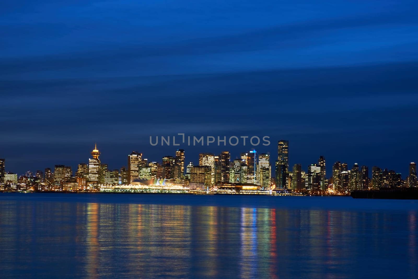 Night city, panoramic scene of downtown reflected in blue water. Vancouver, Canada