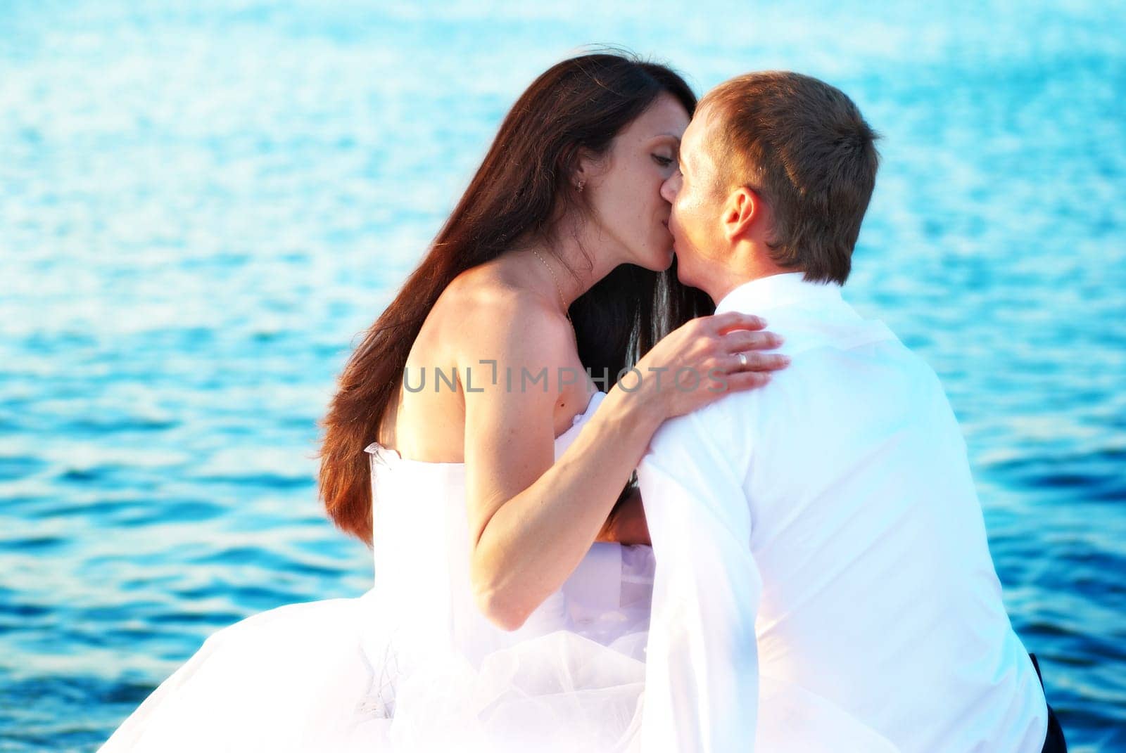 Beautiful wedding couple - bride and groom kissing at the beach. Just married