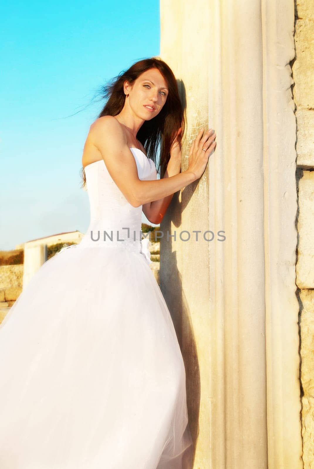 Portrait of beautiful bride in white dress near the old wall.