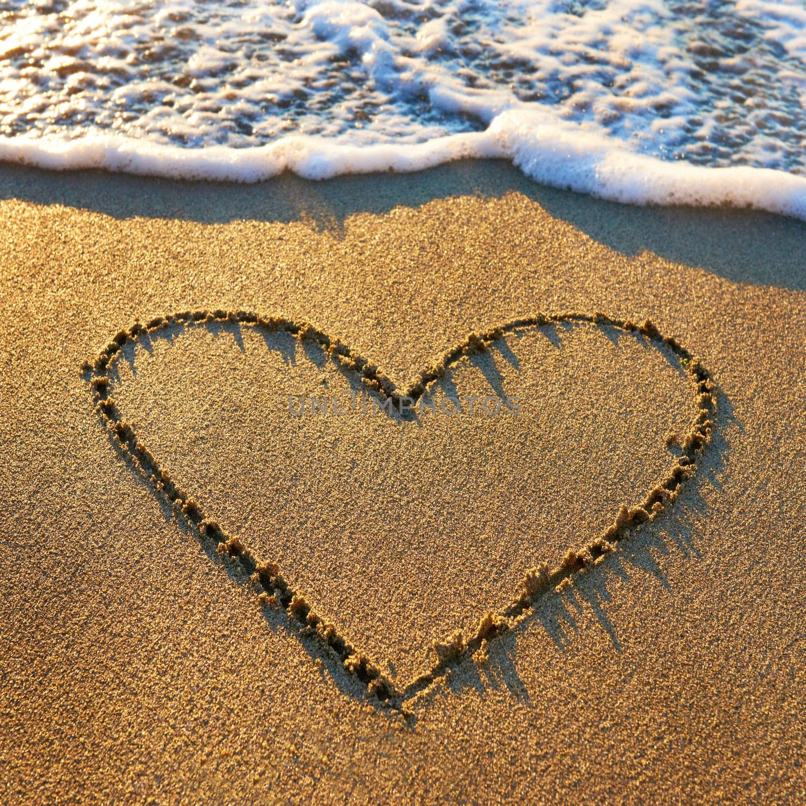 Heart that had been drawn on the beach sand with sea foam and wave