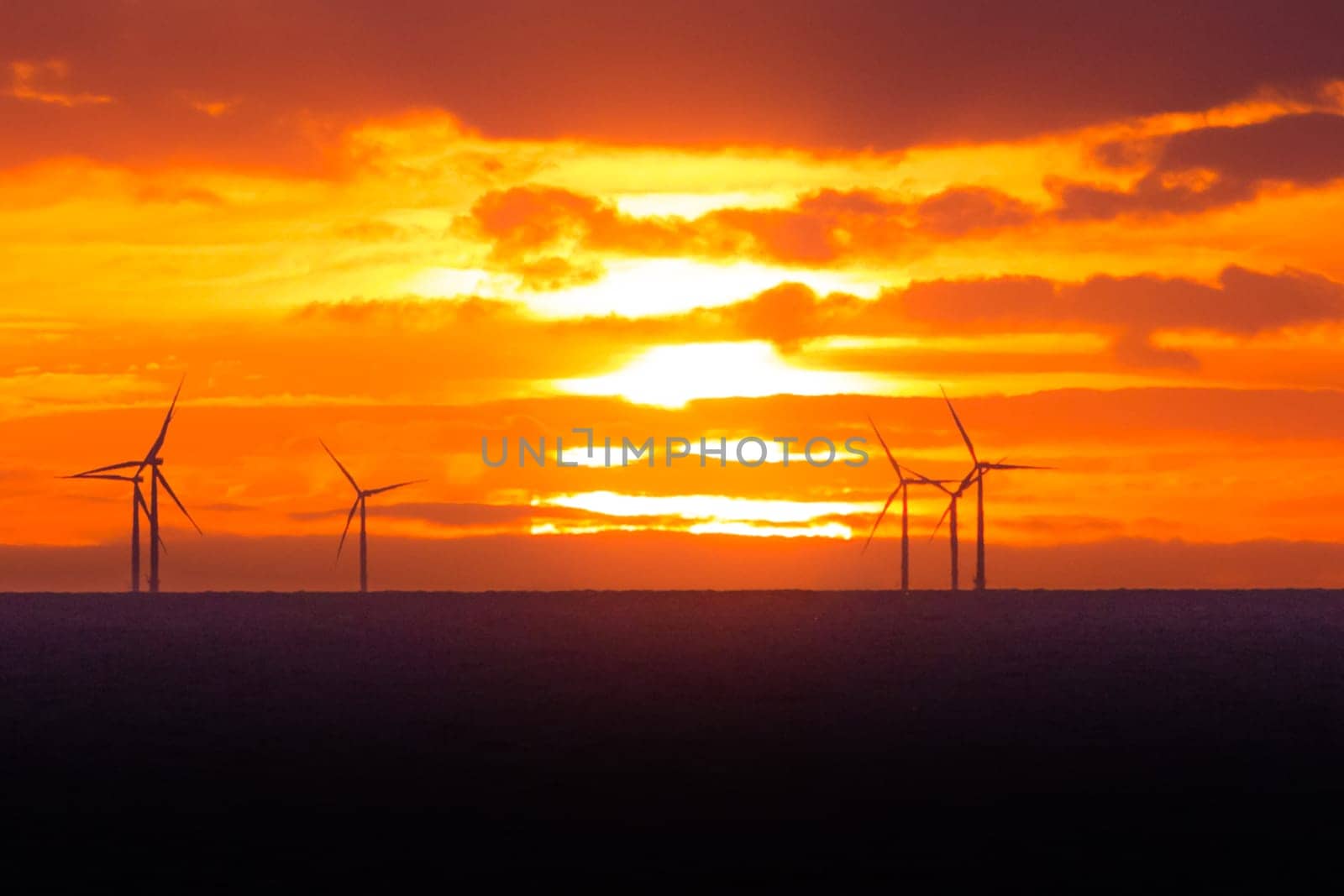 Many energy stations on sea water, clouds in the sky. Sustainable regenerative renewable industry business preventing climate change.