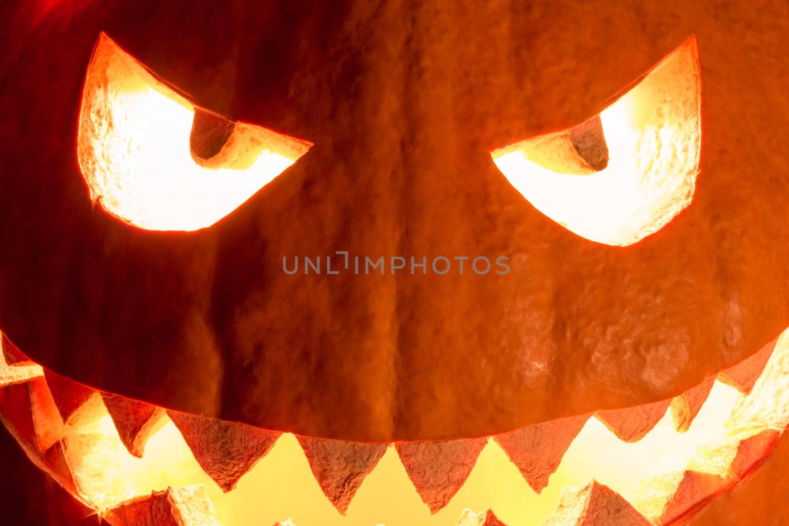Big helloween symbol has a glowing closeup mad face and smiling with sharp teeth and bad look. Black orange nightmare of October 31st.