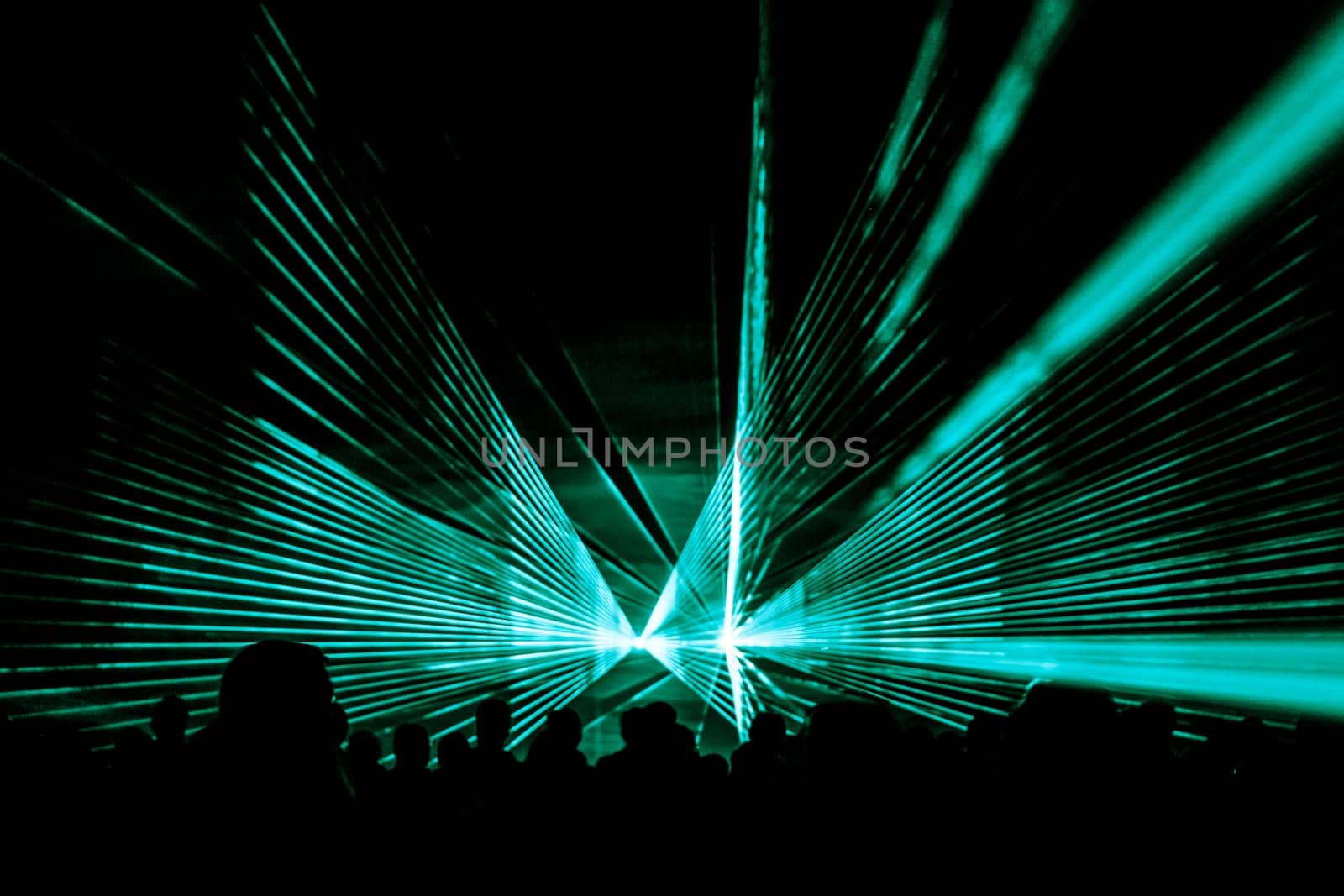Luxury entertainment with audience silhouettes in nightclub event, festival or New Year's Eve. Beams and rays shining colorful lights.