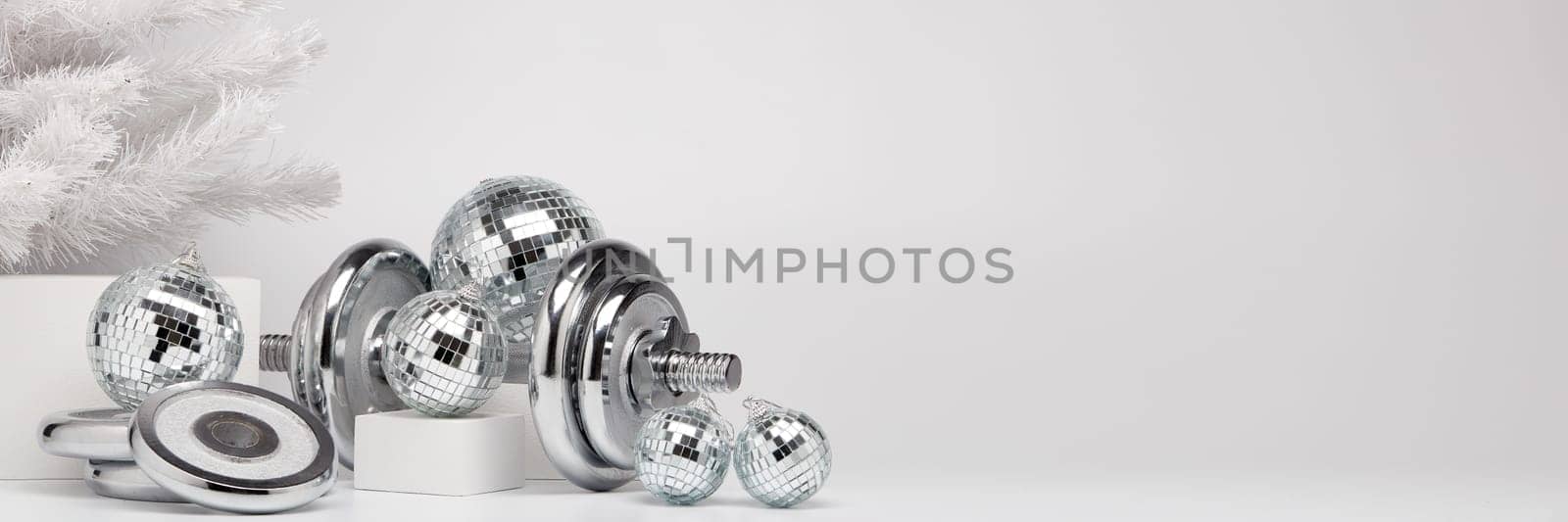 Dumbbells, Christmas fir tree and mirorr balls on white background with copy space. For design of advertising, web design. Christmas and New Year. Fitness, sport or healthy lifestyle concept.
