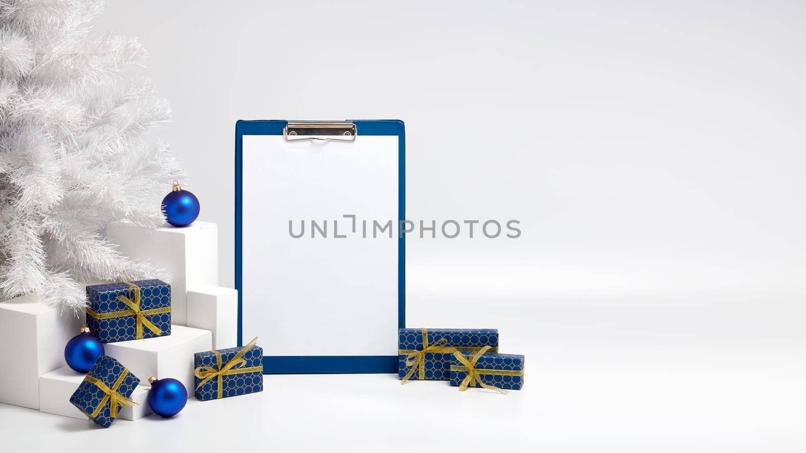 Gift boxes, blank clipboard, fir tree and Christmas decoration on white background with copy space. Christmas and New Year. For advertising. Greeting card. Winter sale