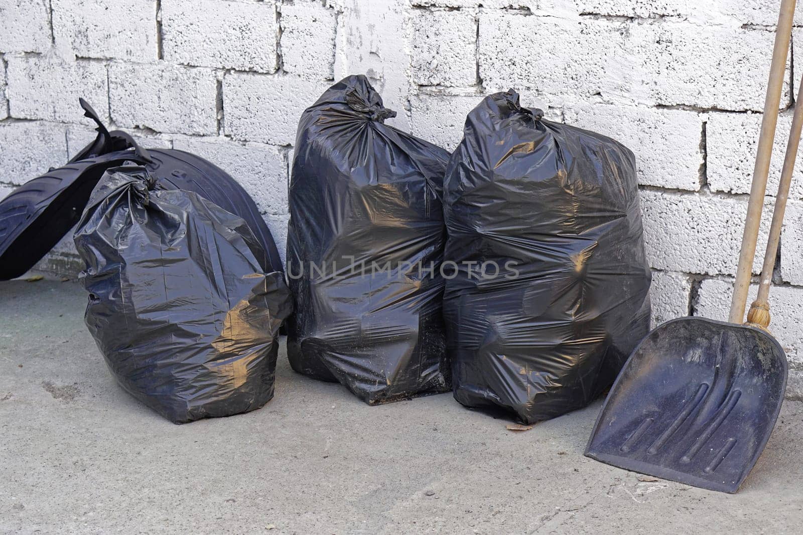 Three big blacks trash bags in front of wall