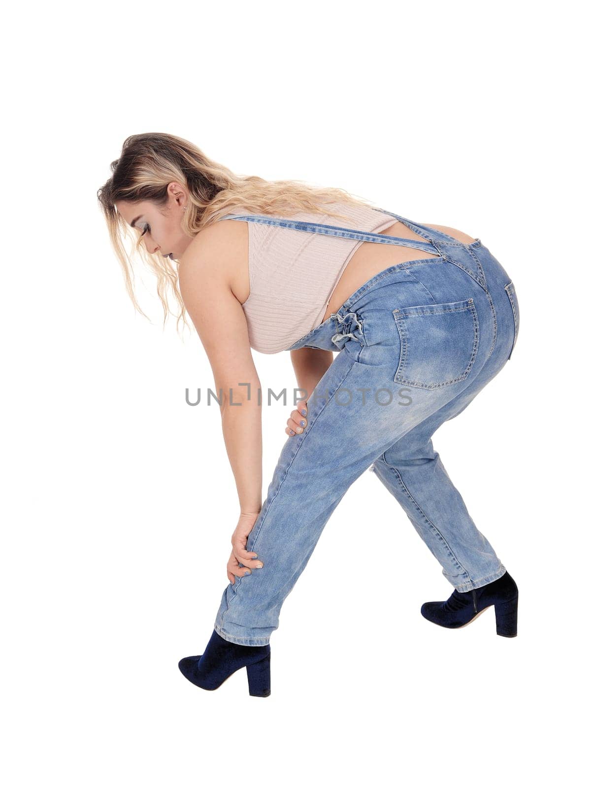 A nice young woman in working jeans and a beige top bending .forwards, isolated for white background.