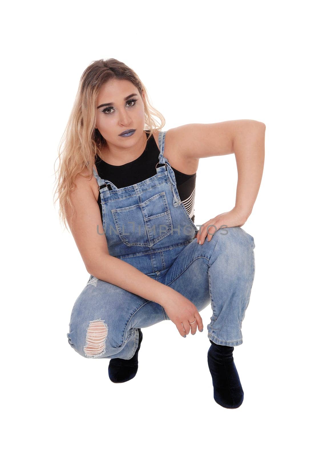 A lovely young blond woman in working jeans crouching on the floor.in the studio, isolated for white background.