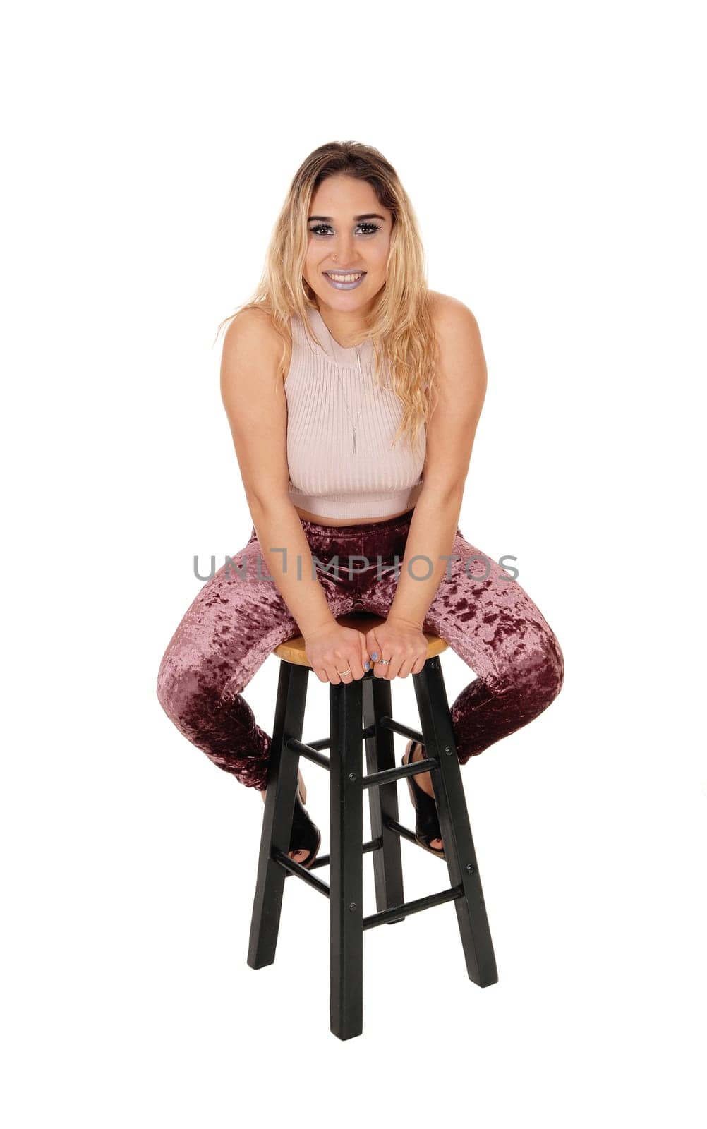 A lovely young woman in tights and a short sweater sitting on a bar.chair in the studio, isolated for white background.