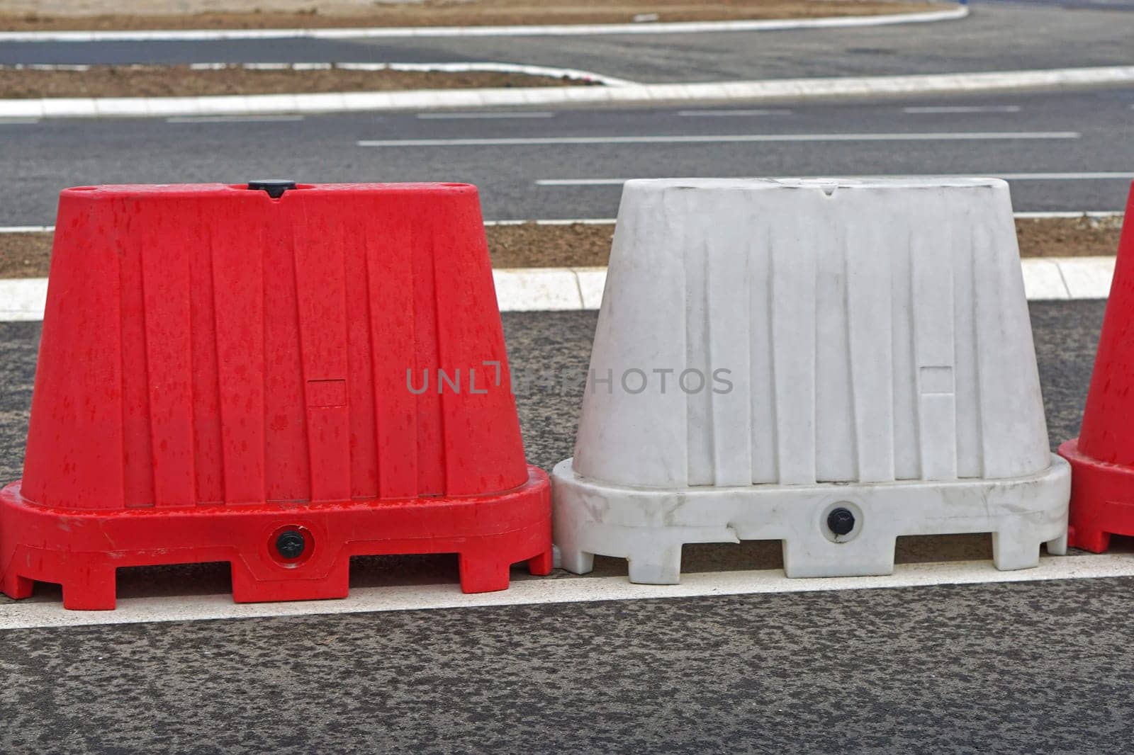Red and white plastic road barrier filled with water