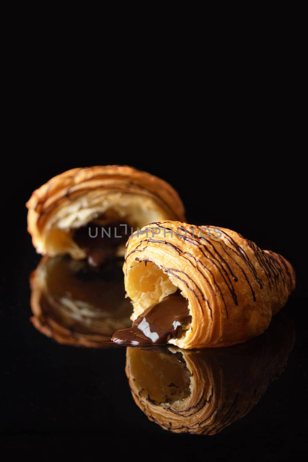 Croissant with chocolate flowing out on a black glass elegant background