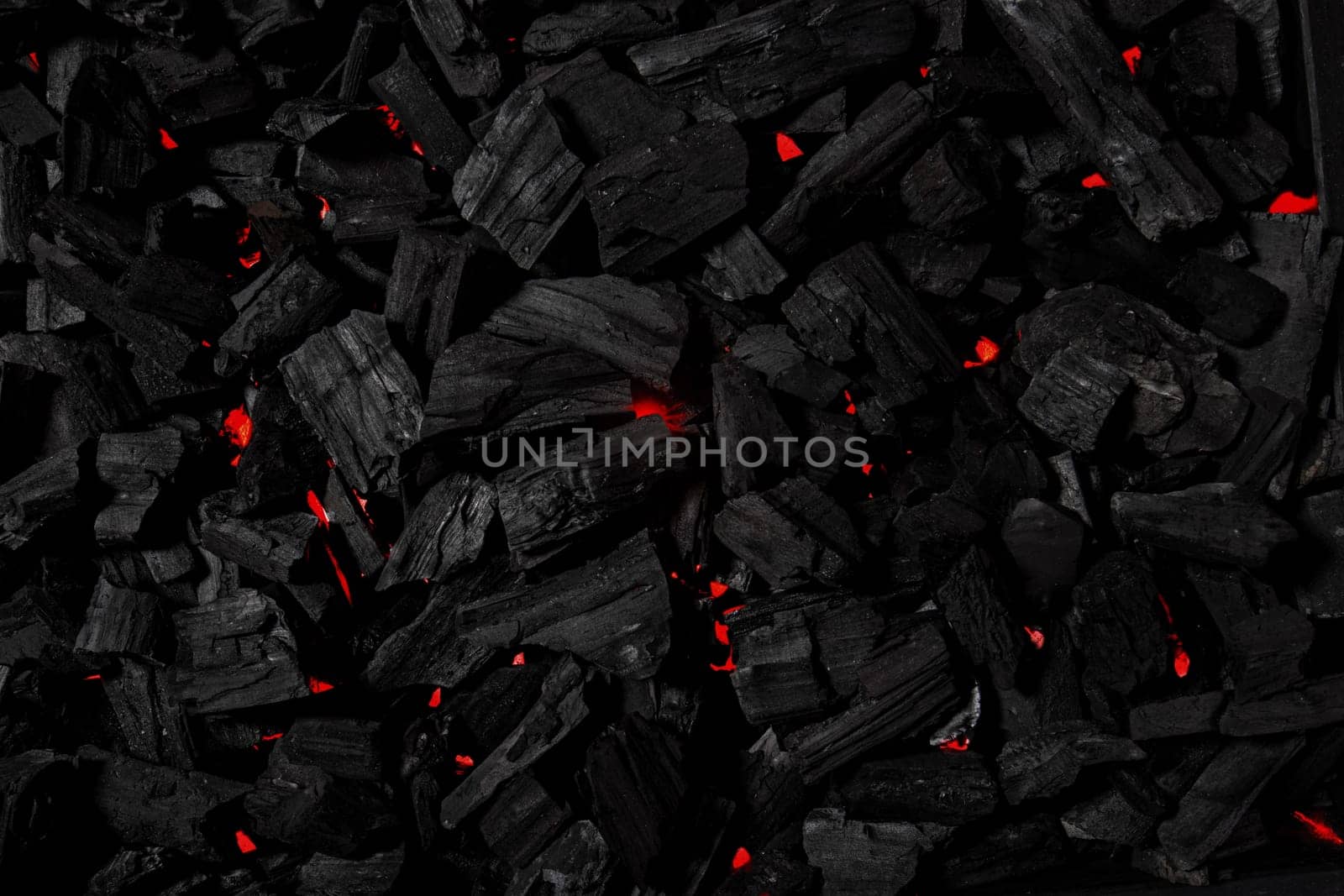 Black coal background illuminated with red light like fire underneath
