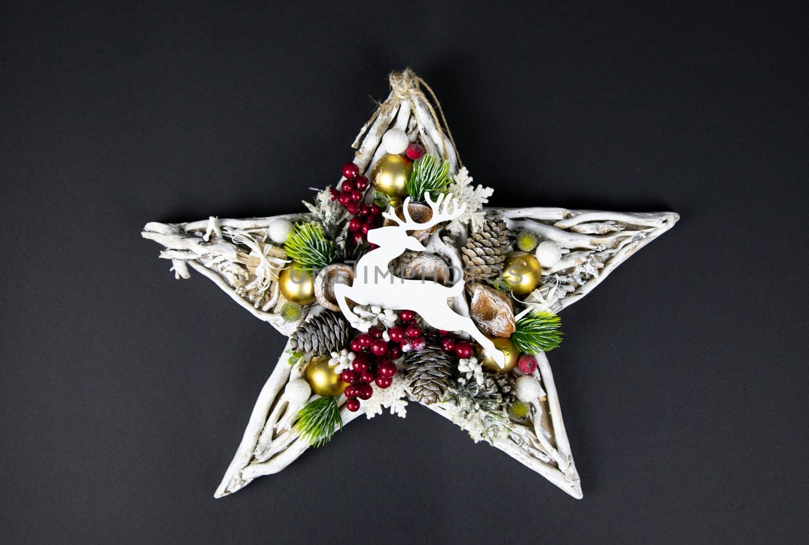 Handmade star decorated with cones and cranberries with christmas deer