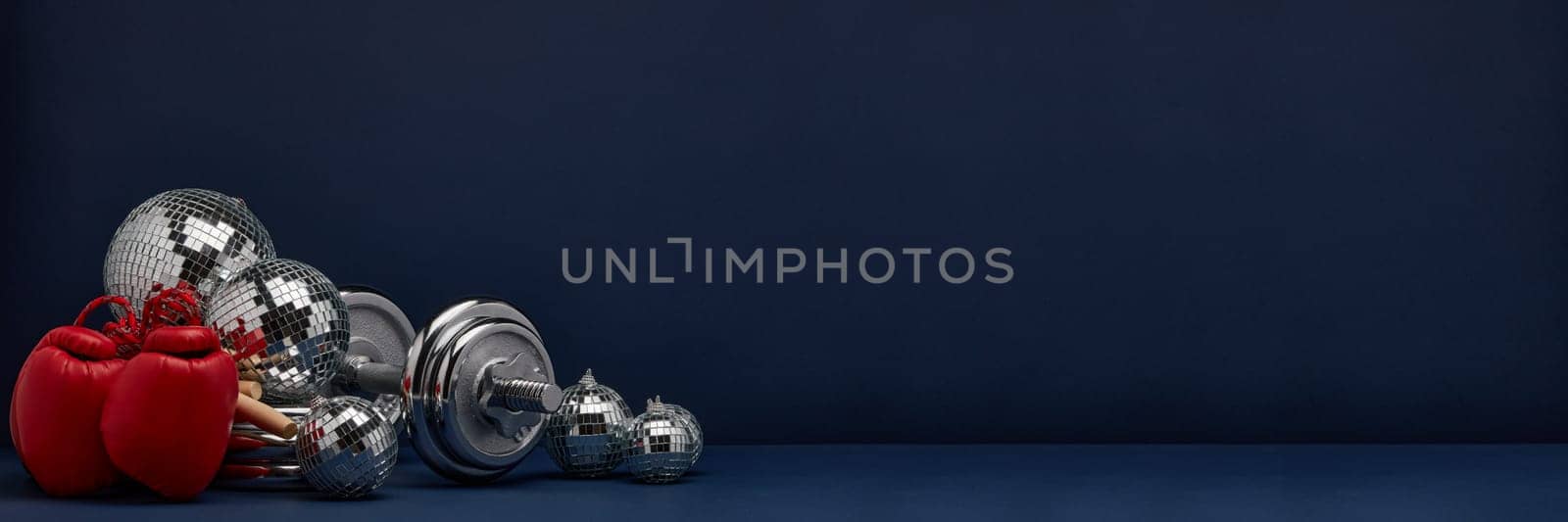 Dumbbell, boxing gloves, skipping rope, mirorr balls on dark blue background with copy space. For design of advertising, web design. Christmas and New Year. Fitness, sport or healthy lifestyle concept