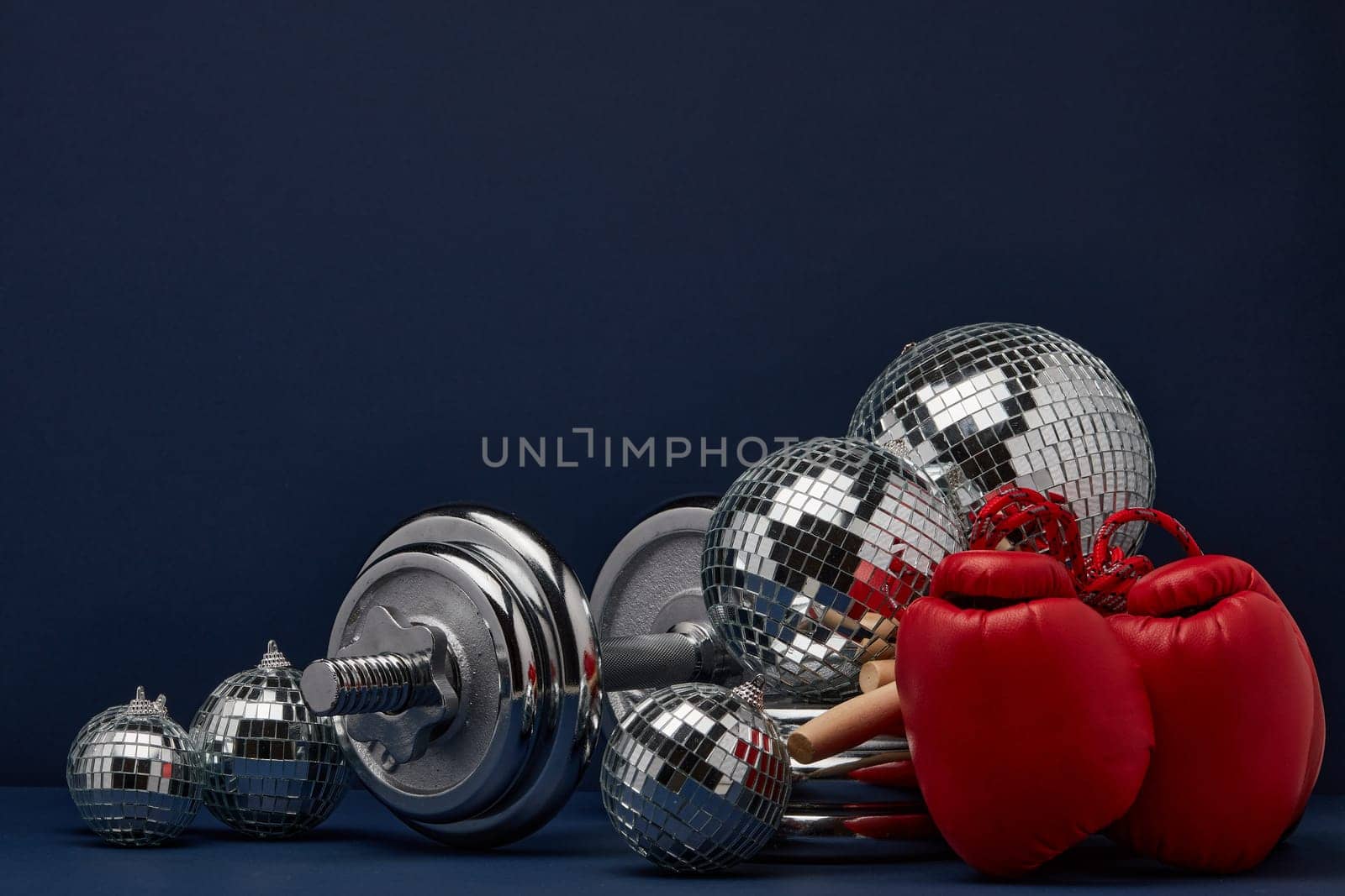 Dumbbell, boxing gloves, skipping rope, mirorr balls on dark blue background with copy space. For design of advertising, web design. Christmas and New Year. Fitness, sport or healthy lifestyle concept