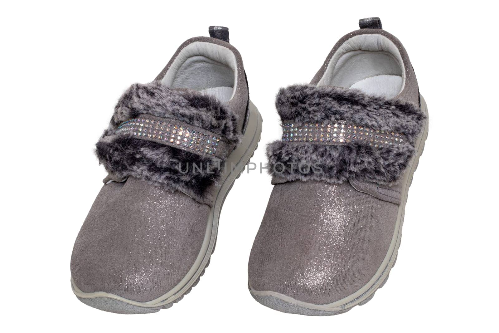 Child shoes fashion. Close-up of a pair beautiful gray silver suede sneaker or sports shoes for girls with fur and rhinestone decoration isolated on a white background. Macro of kids trendy footwear.