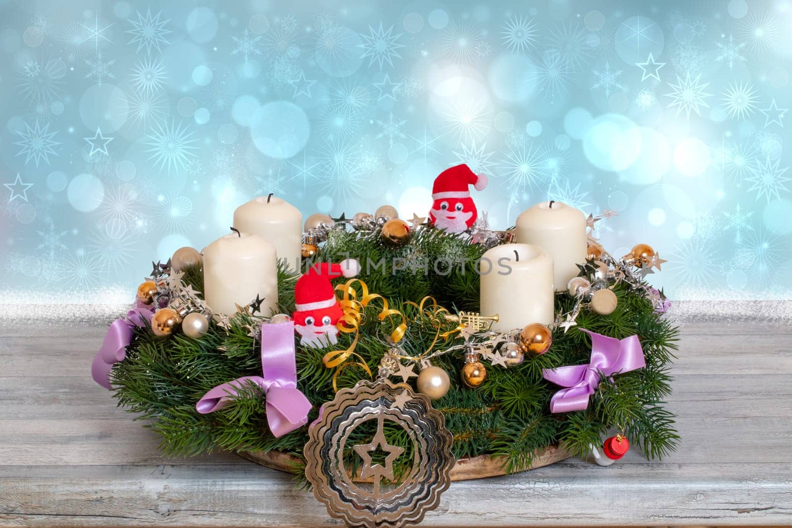 Christmas wreaths. Close-up of a colorful christmas wreath with candles and decorations on a rustic wooden table in front of abstract blue winter xmas or New Year background. Space for design.
