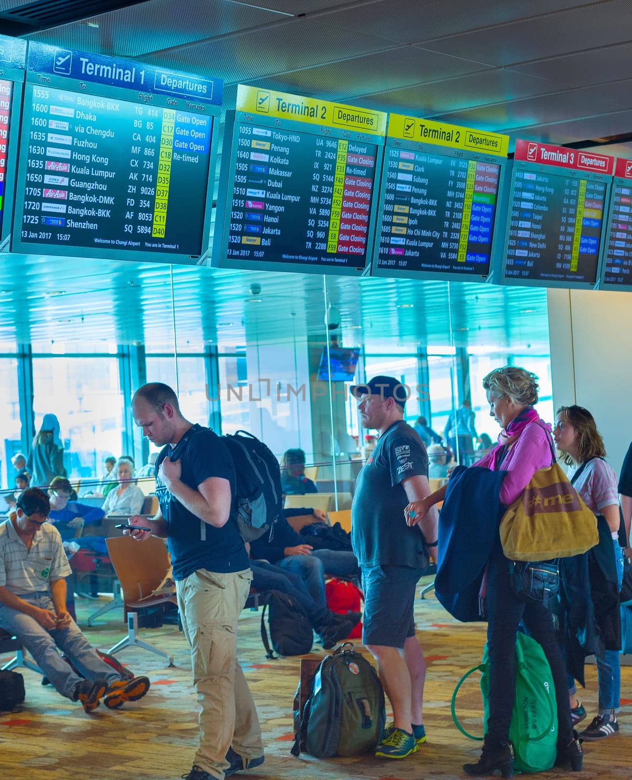 SINGAPORE - JANUARY 13, 2017: People waiting in queue at Changi International airport. Flight information desk above the people