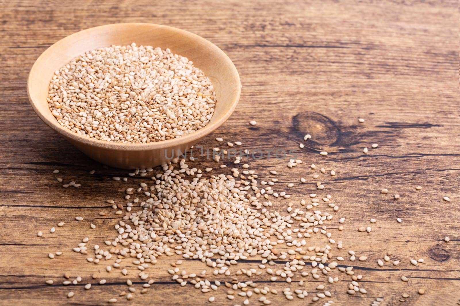 Unpeeled Sesame Seed in a wooden Bowl on brown background