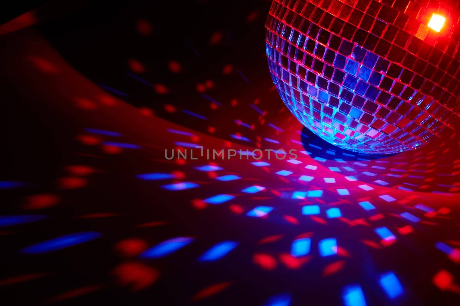 Glittering mirror disco ball on dark background with red blue lighting. Copy space. Weekend or holiday party. Nightclub. For advertising or web design. Entertainment, disco or music show background