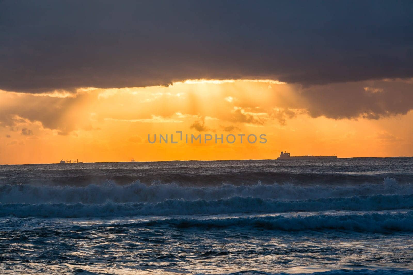 Ocean waves sunrise clouds ships silhouetted in morning color contrast on horizon