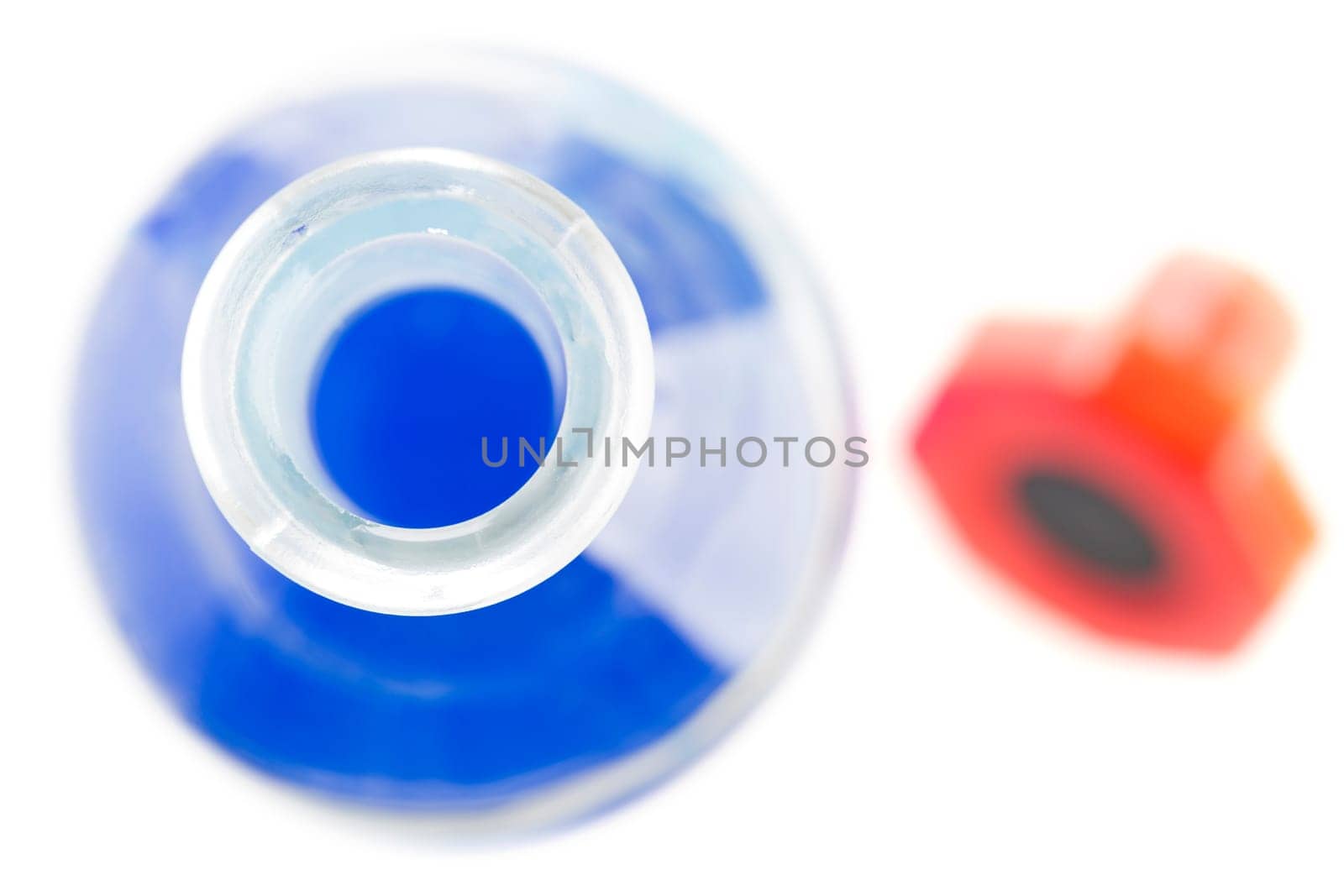 Bottle with blue Liquid from above, with red stopper out of focus.